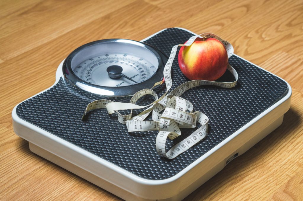 Eine Waage mit einem Apfel und einem Maßband darauf.
Protein hilft beim Abnehmen.